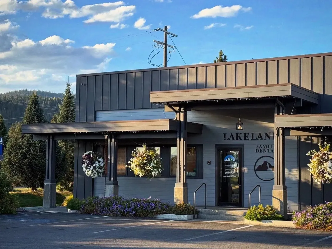 Lakeland Family Dental's office on Highway 41 in Rathdrum at golden hour, with hanging flower baskets and evergreens behind.